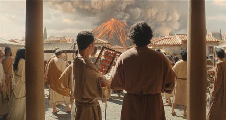 A crowd of people in Pompeii watch Mount Vesuvius erupt