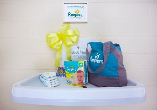a changing table with Pampers diapers and a diaper bag on it