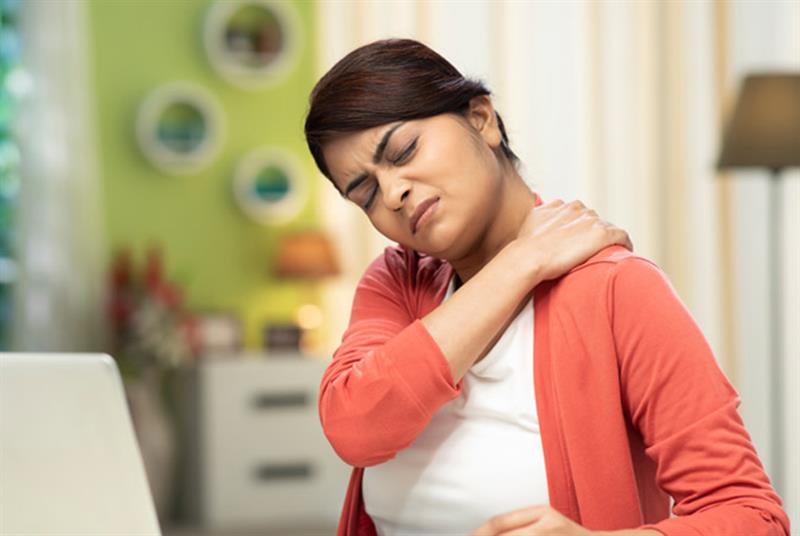 A woman rubbing her shoulder who looks like she is in pain