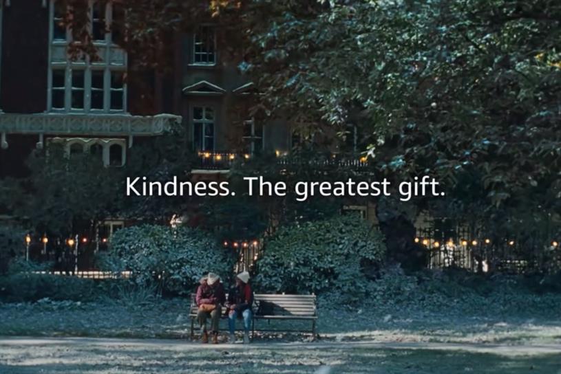 Two women sit on a bench in a park. A tagline, "Kindness. The greatest gift." is in the middle of the screen.