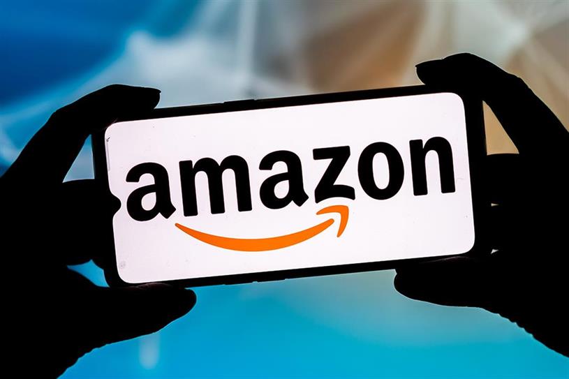  A pair of silhouetted hands hold a smartphone bearing the Amazon logo