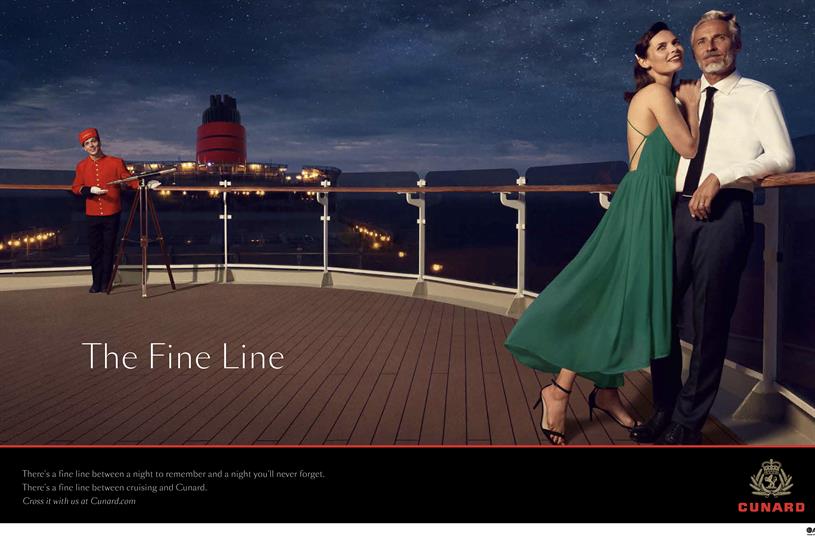 A nicely dressed couple stands on the deck of a cruise ship at night time, gazing at the stars