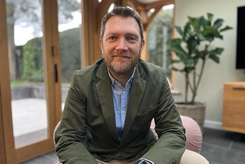 A photo of Tim Pearson sitting down in his lounge.