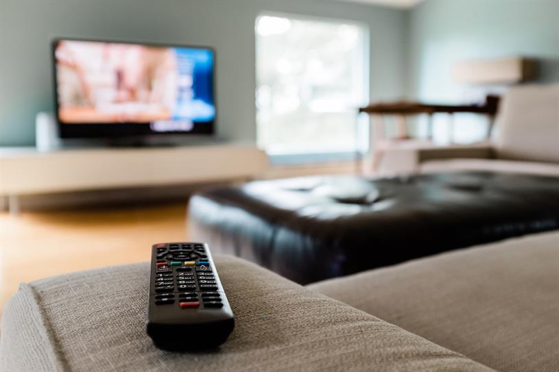 A remote control pictured with a TV in the background. (Photo: Getty Images)