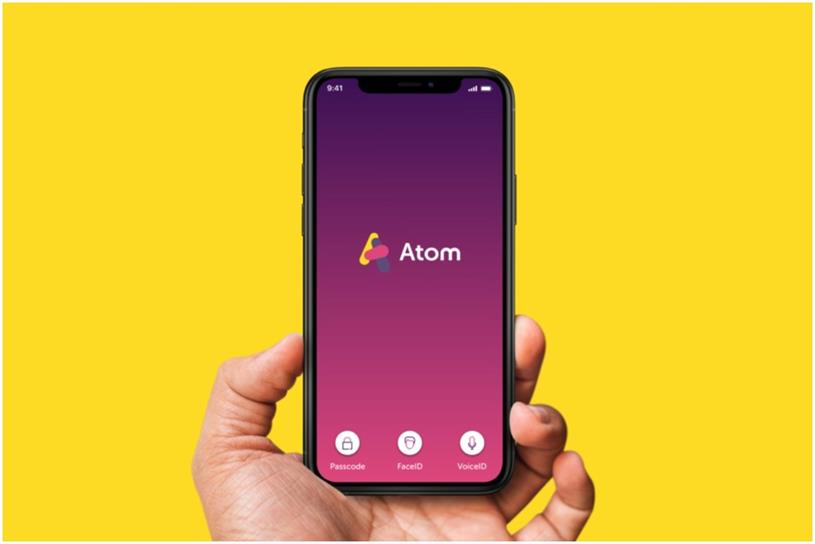 Hand holding a smartphone with the Atom Bank logo on the screen