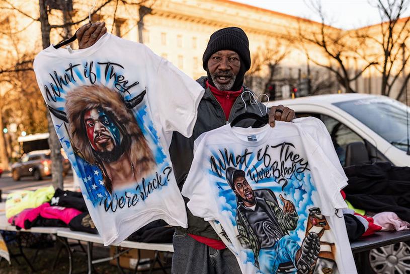 Man holding What if They Were Black January 6 Capitol Riot shirts 