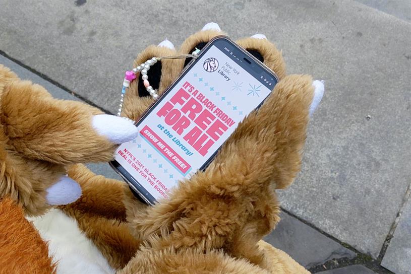 New York Public Library lion mascot holding iPhone with NYPL app.