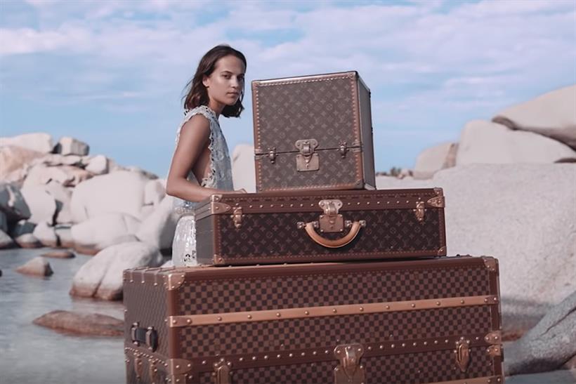 A Louis Vuitton ad in which a model moves suitcases at a beach