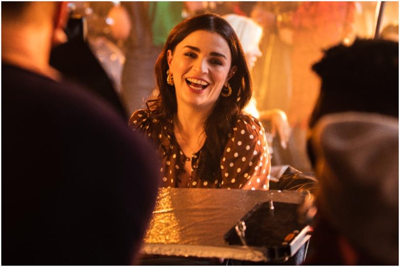 Aisling Bea on set laughing in a spotted blouse 
