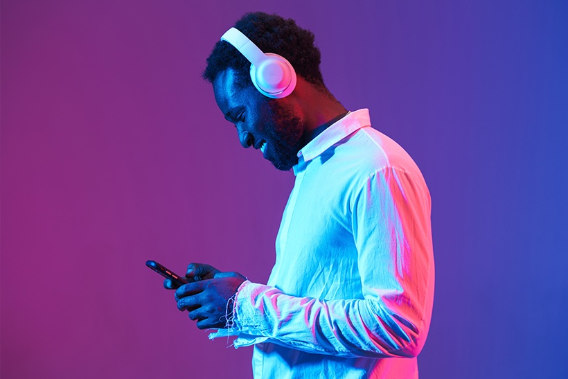 Man listening to music on headphones holding smart phone