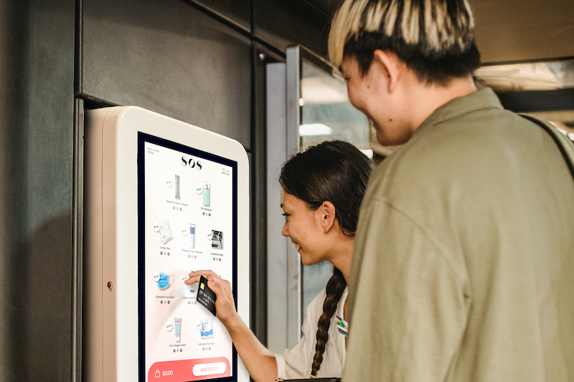 Two customers using healthcare company SOS app on touch screen kiosk