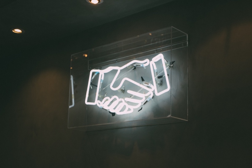 Neon sign of two hands shaking