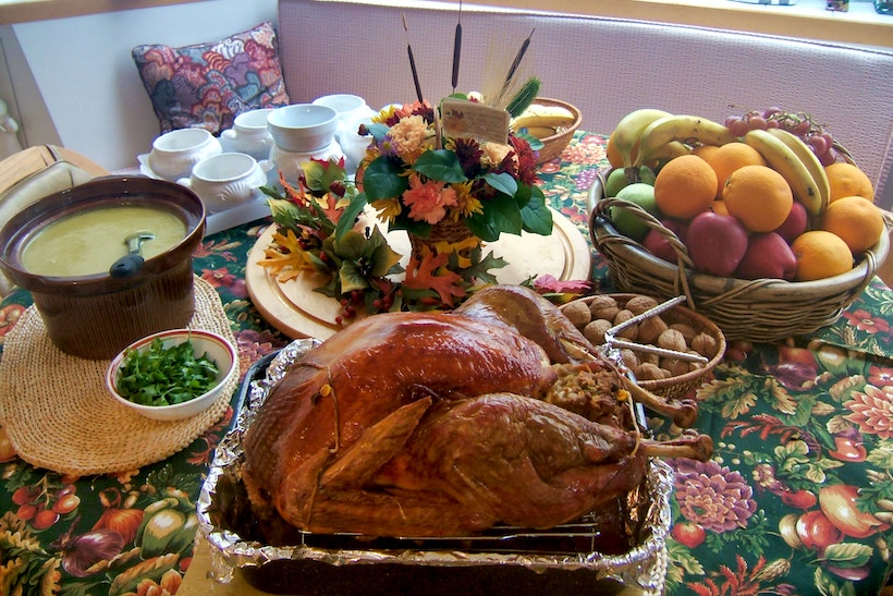 Thanksgiving dinner table with turkey, gravy, and fruit basket.