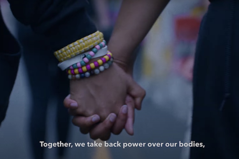 Two people holding hands with the caption "Together, we take back power over our bodies"