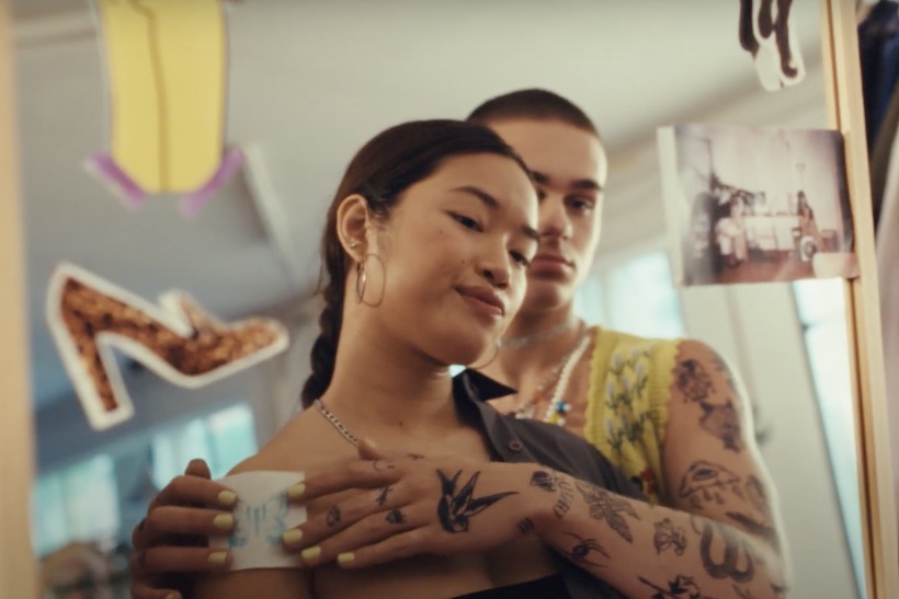 Two young tattooed people looking a mirror