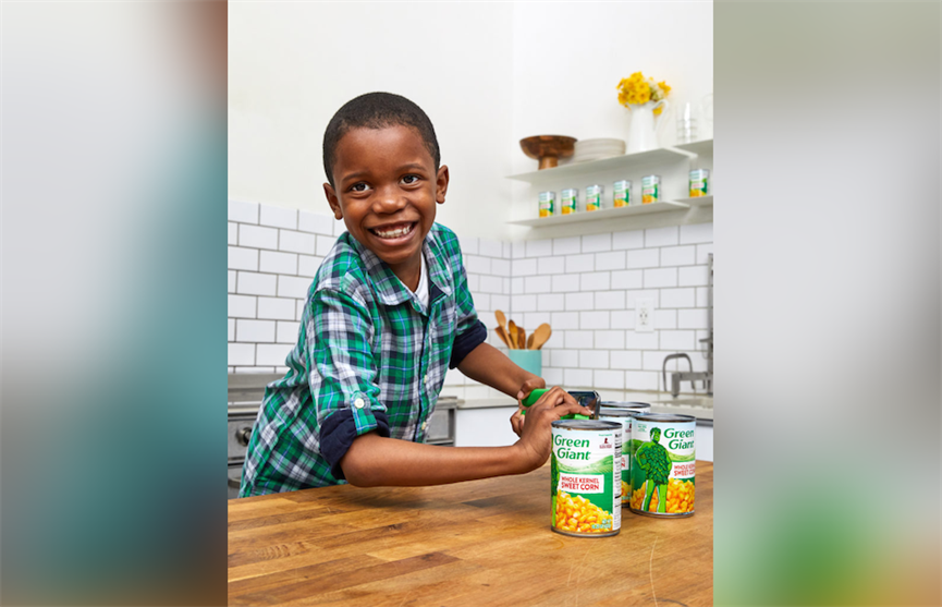 Corn Kid Tariq opening a can of Jolly Green Giant branded corn