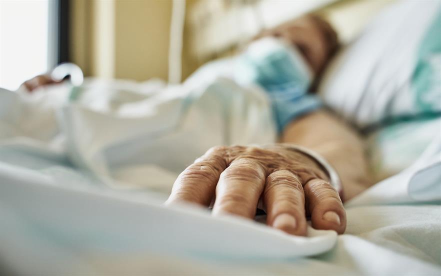 Close up fingers of a patient wearing a mask on hospital bed. 