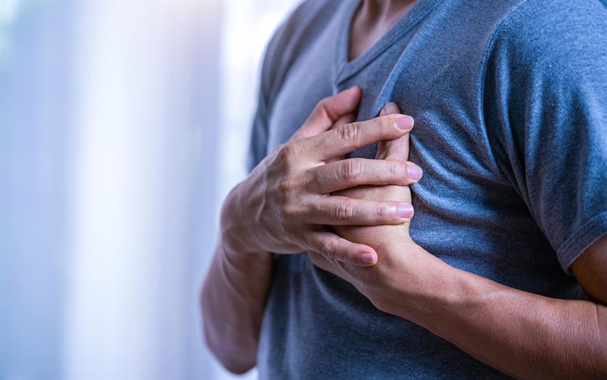 Man wearing a blue tshirt with hands over heart indicating pain. 