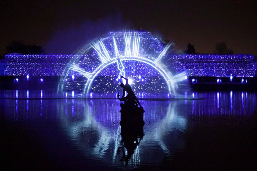 Blue Christmas lights display with clock projection reflected on water at Kew Gardens