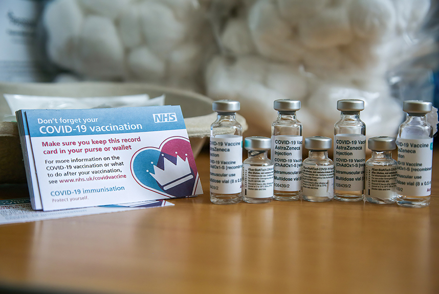 Vials of AstraZeneca and Pfizer vaccines and a vaccination record card