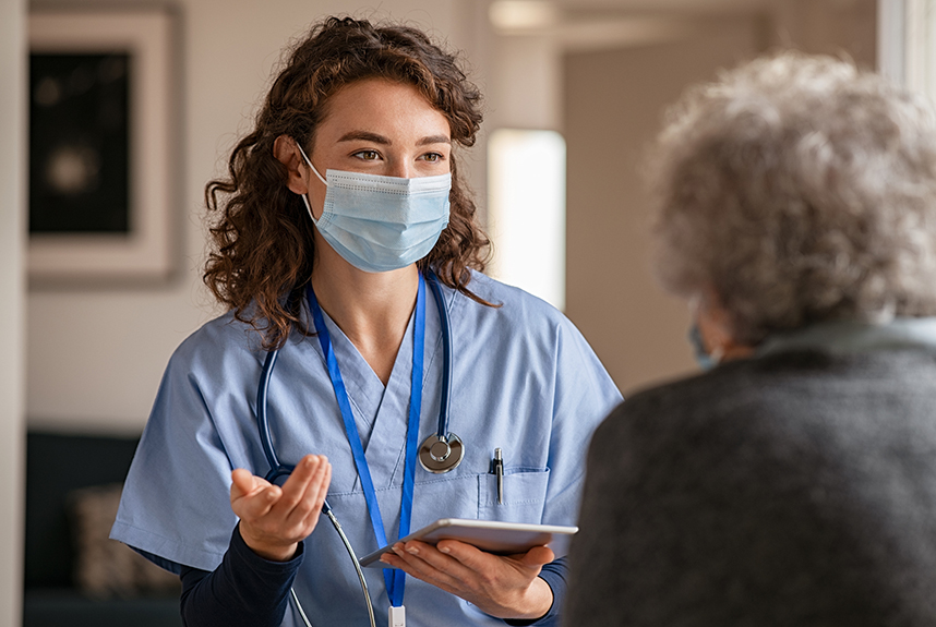 Doctor wearing a face mask talking to an elderly patient