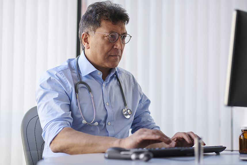 Middle aged male doctor using a computer