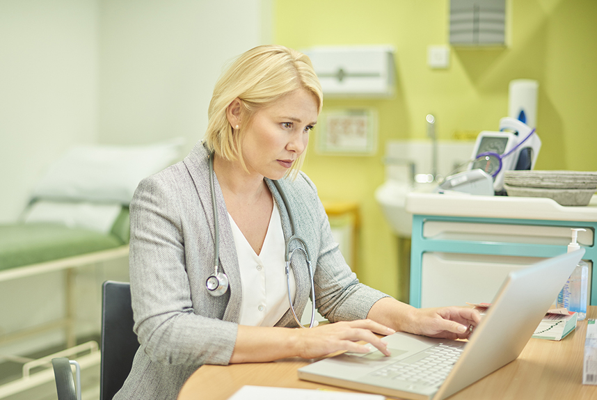 Female GP using a computer in a consultation room