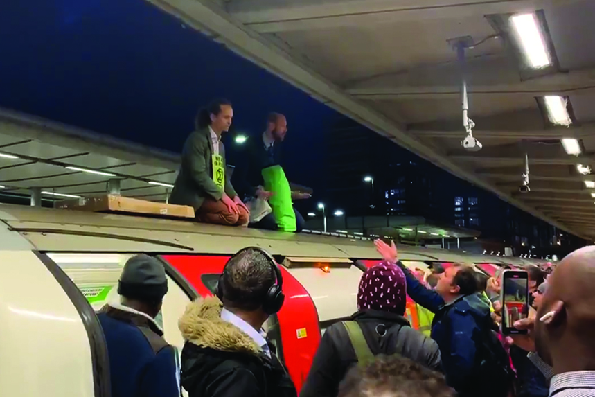 Extinction Rebellion protestors hold up a train at Canning Town tube station