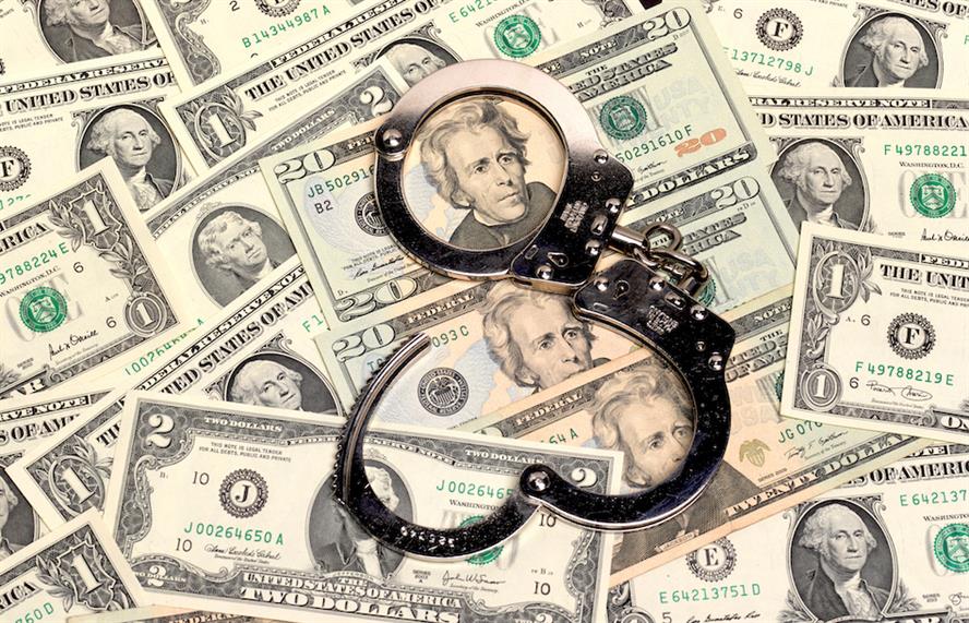 Handcuffs on top of dollar bills, displaying corruption and fraud concept