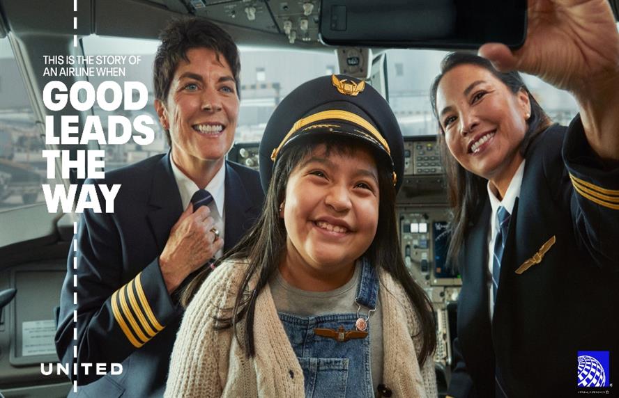 Smiling girl wearing an airplane captain's hat with pilot and copilot by her side