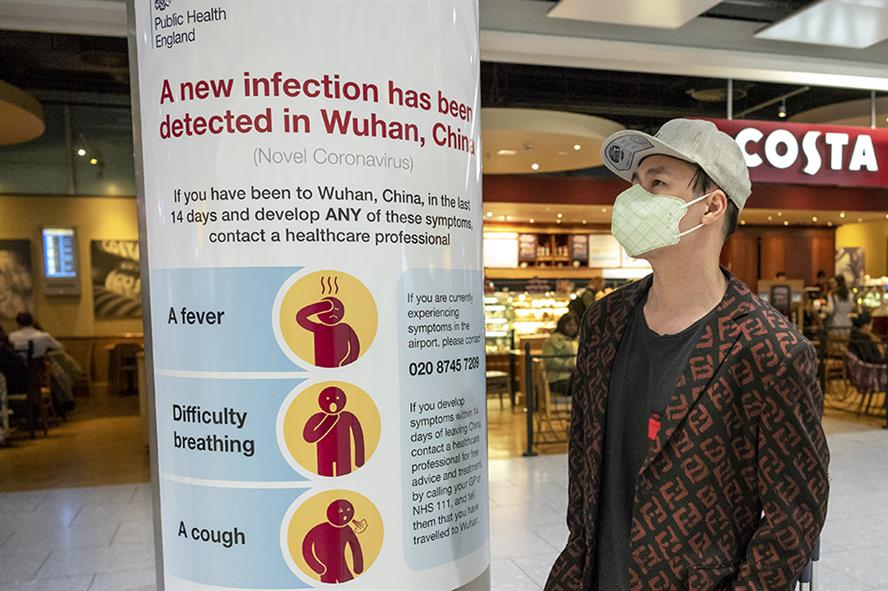 A man looks at Public Health England's infection control poster at Heathrow (Alex Lentati/LNP/Shutterstock)