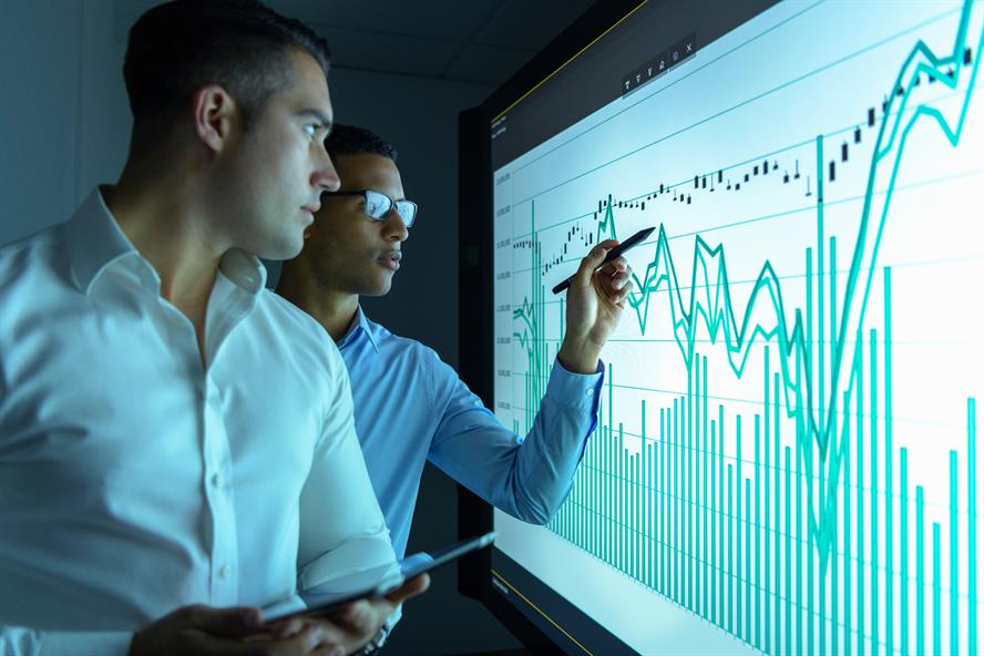 Picture of people in suits looking at a graph on a big screen