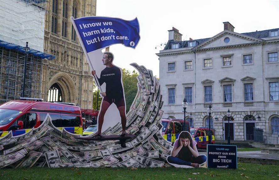 Caption: An installation depicting Mark Zuckerberg surfing on a wave of cash outside Parliament in London. (Photo credit: Getty Images). 