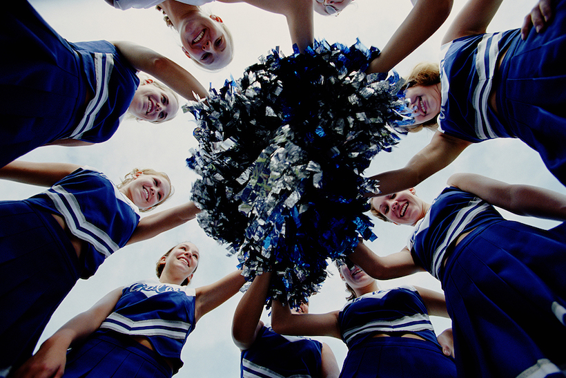 Group of cheerleaders holding pompoms in a circle