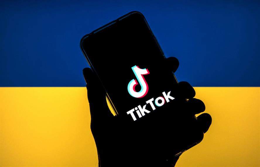 TikTok app logo on cell phone screen in front of Ukraine flag