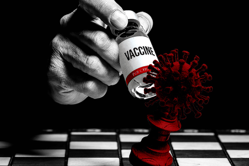 Handing holding corovirus vaccine bottle as a chess piece knocking a COVID-19 chess piece off a board